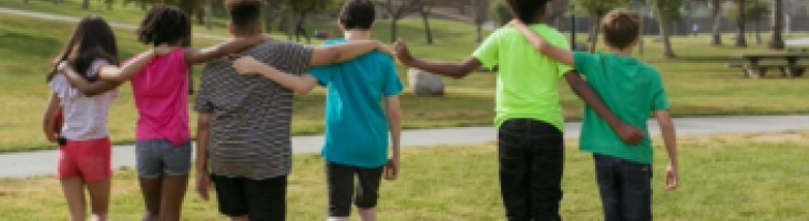 children walking in park with arms around each other