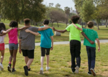 children walking in park with arms around each other
